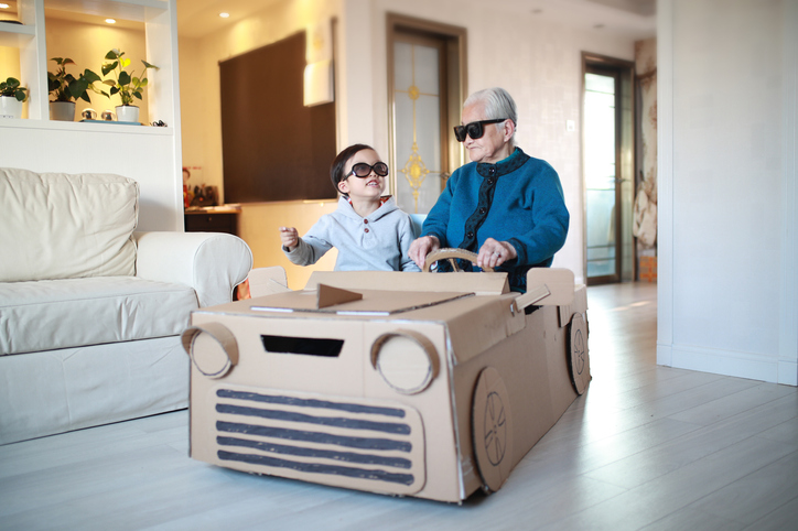Young boy with his grandma in a cardboard car.
