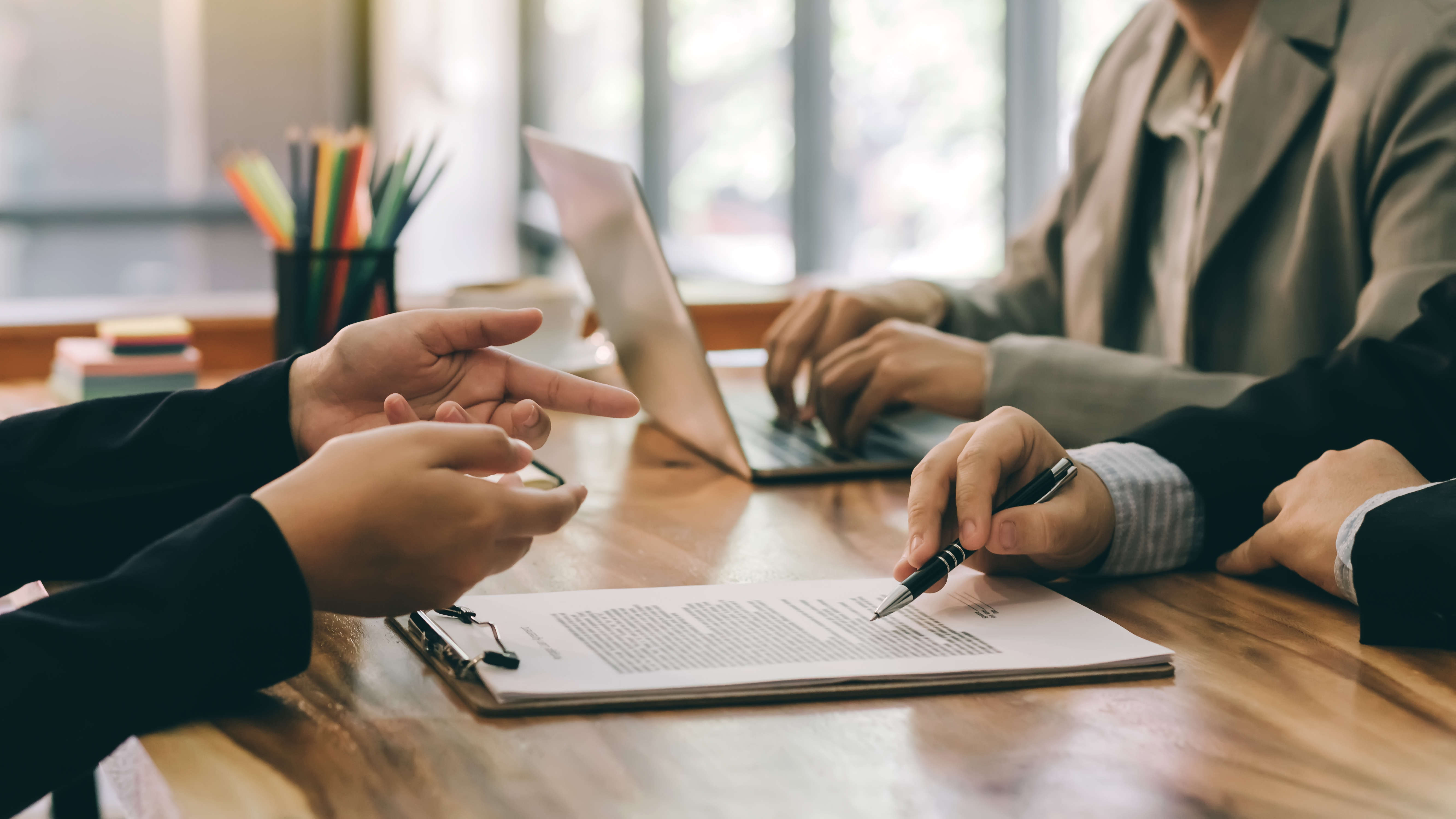 Three sets of hand doing business over a desk