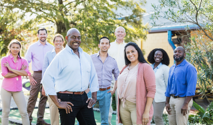 Group of diverse individuals standing outside looking at the camera.