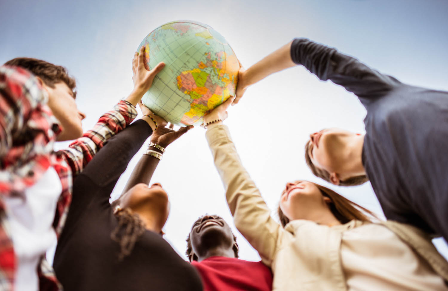 group of diverse people uplift a globe of the earth