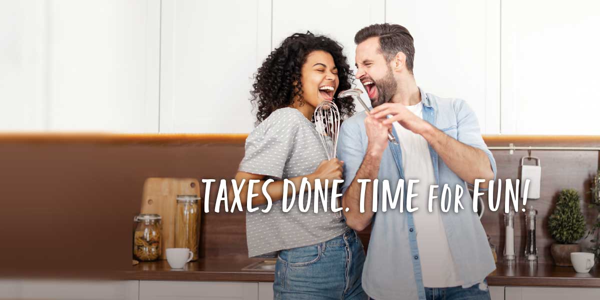 A young couple in a kitchen. The woman is singing into a whisk and the man is looking at her and singing into a ladle. Text over the image reads Taxes Done. Time for Fun!