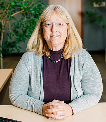 Photo of Supervisory Committee Member Marta Huff sitting at a desk.